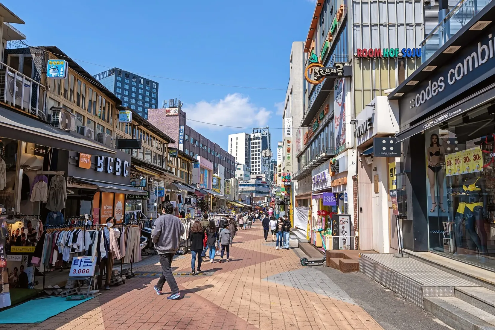 Rua de pedestres em Hongdae, Seul, cheia de jovens, lojas e apresentações de rua