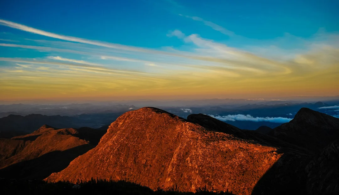 Pico da Bandeira iluminado pela luz alaranjada do amanhecer, na Serra do Caparaó
