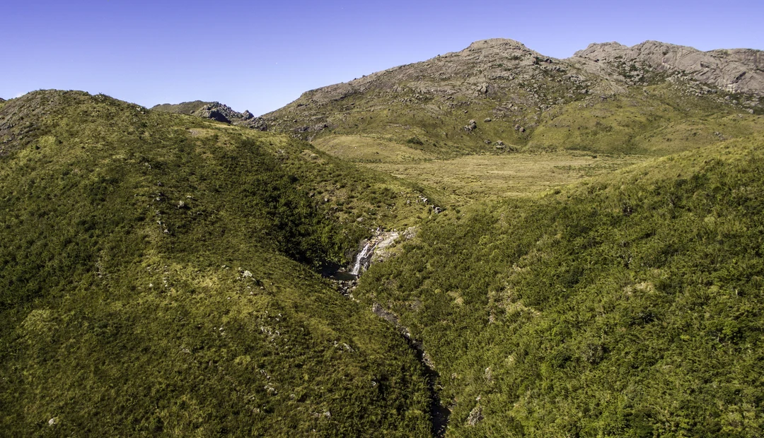 Crista verde e rochosa da Pedra do Sino de Itatiaia, com vale abaixo