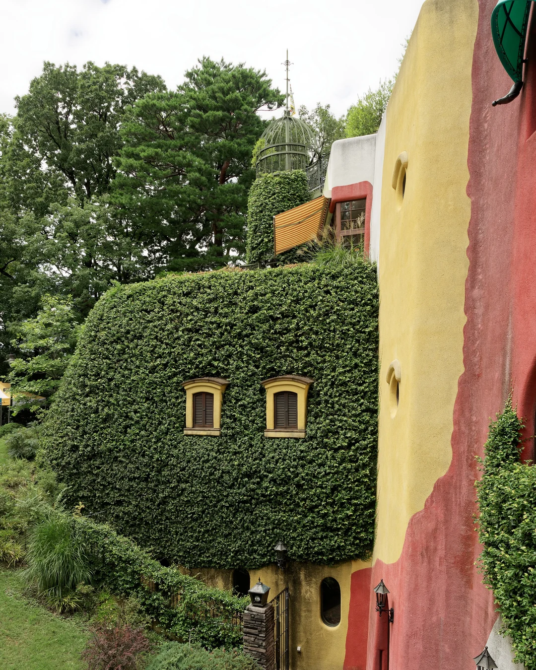 Fachada coberta de hera do Museu Ghibli, em Mitaka, Tóquio, com janelas coloridas