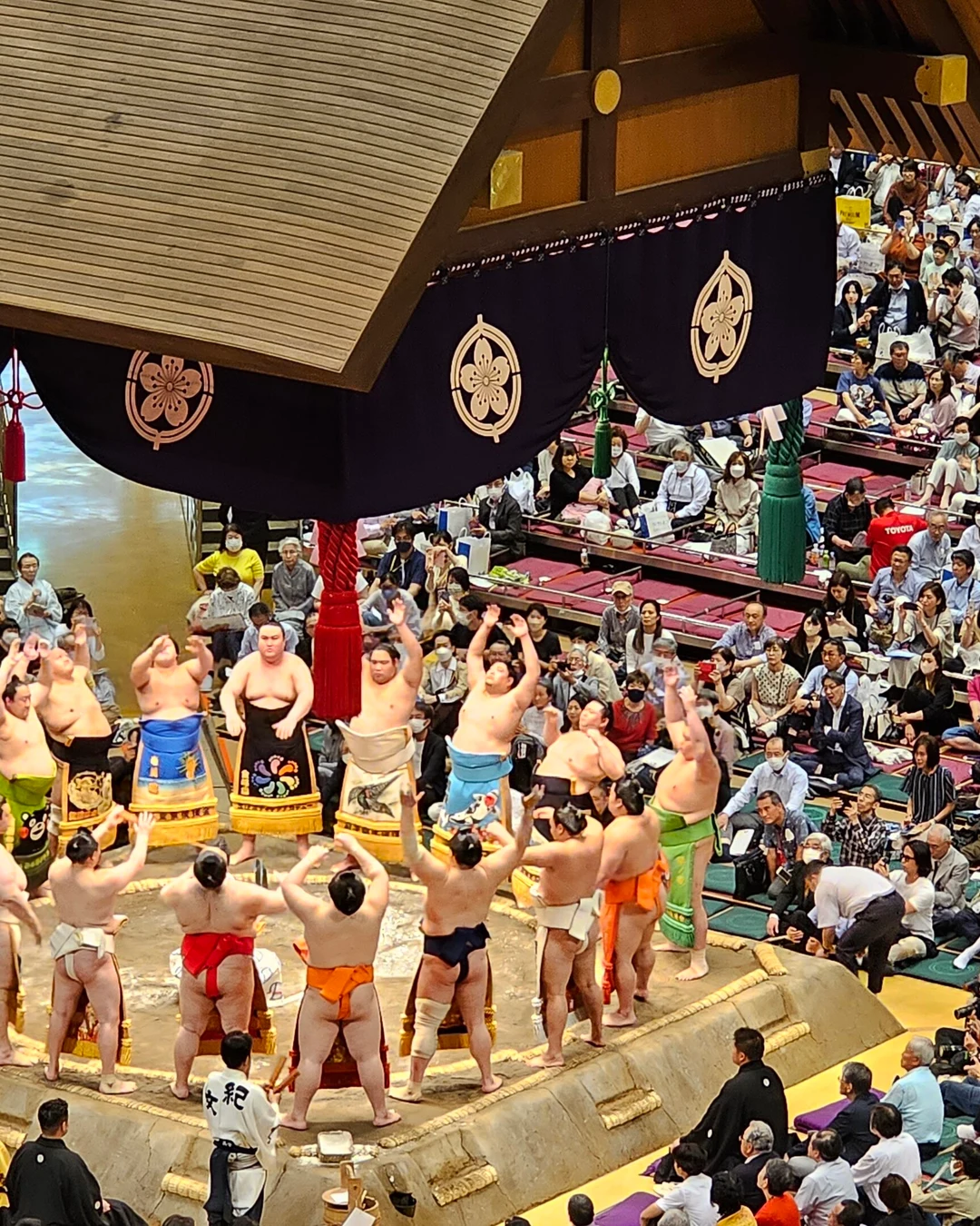 Lutadores de sumô de avental cerimonial em círculo no ringue do Ryogoku Kokugikan, em Tóquio, durante a cerimônia de entrada
