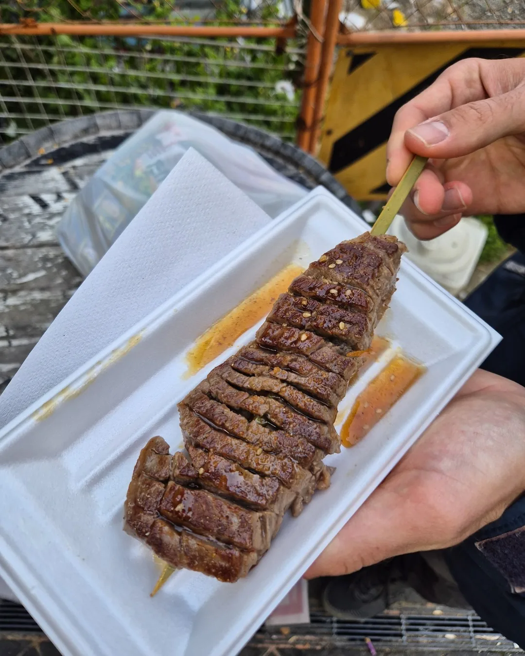 Espetinho de wagyu fatiado, com molho, comido em Osaka