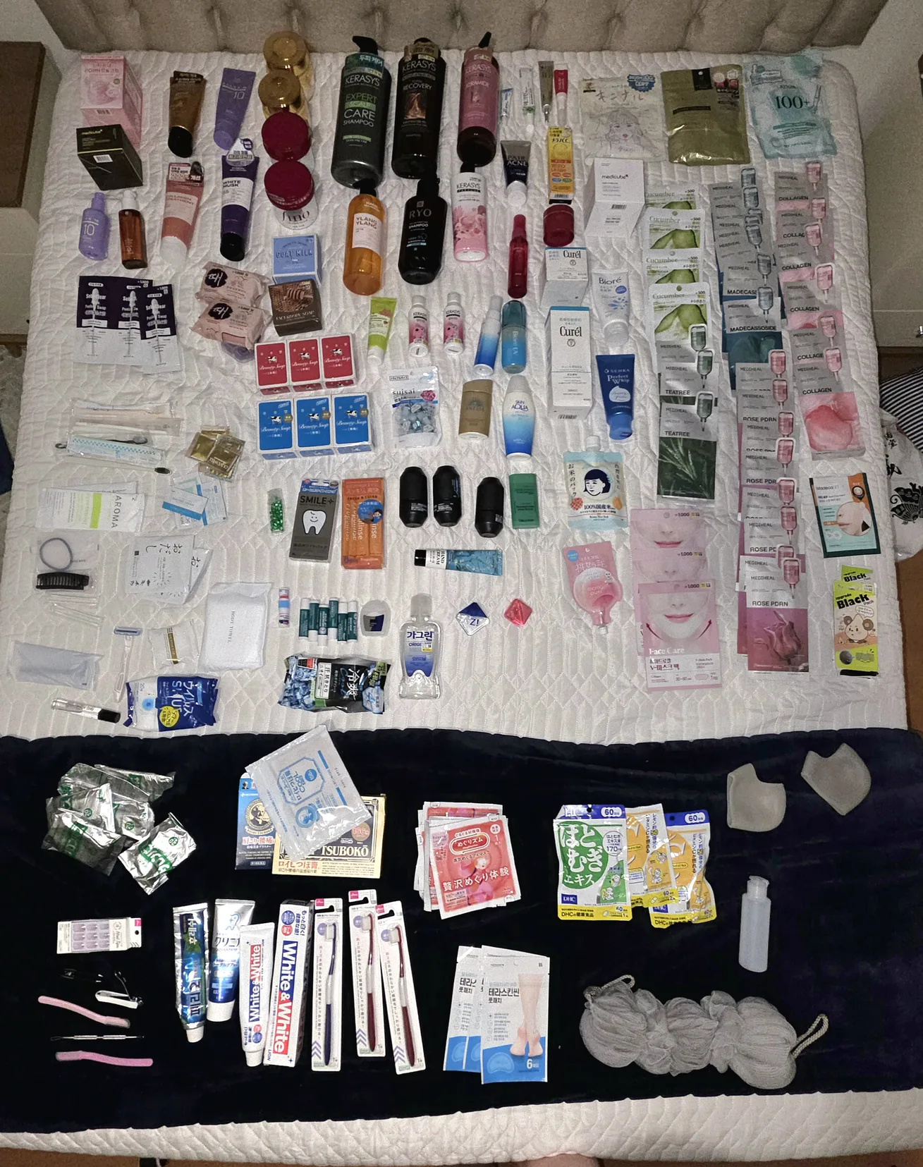 Cama coberta de produtos de skincare, cabelo e farmácia comprados no Japão, vista de cima